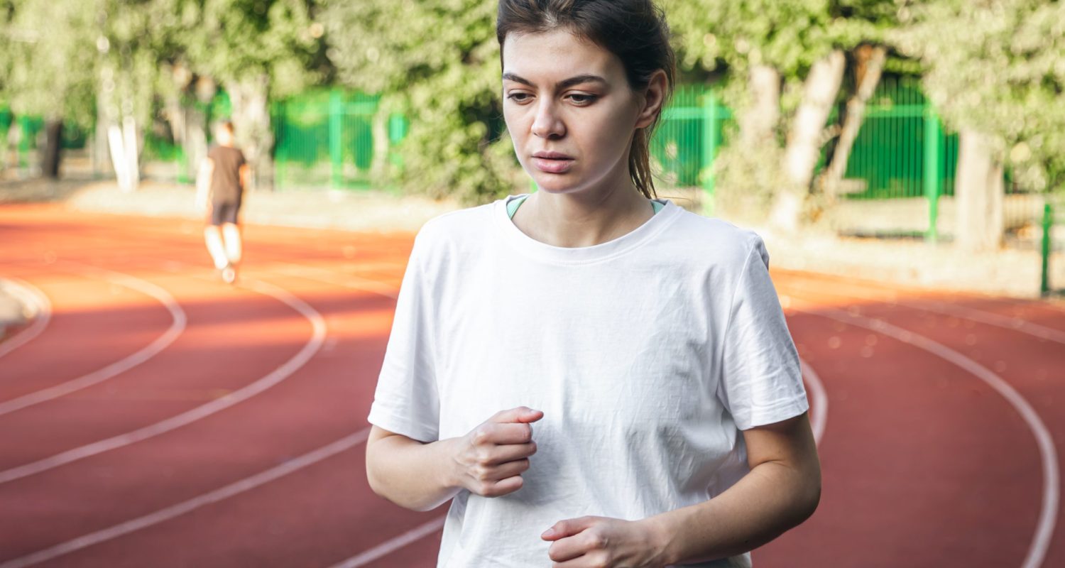Attractive young woman in sportswear jogging at the stadium, woman outdoor on a track for running.